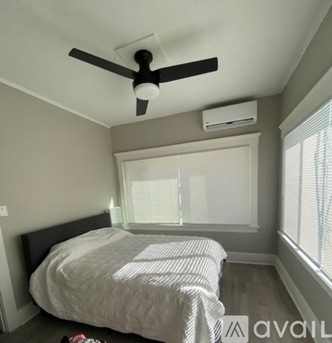 A bedroom with a bed, a ceiling fan, and a window with blinds.