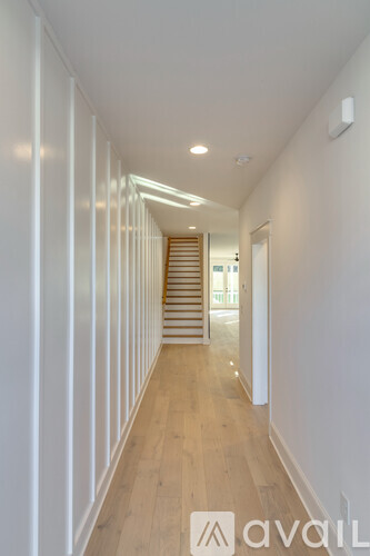 A long hallway with wooden floors and white walls.