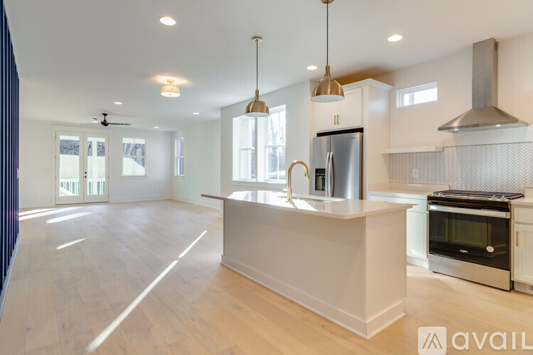 A modern kitchen with a stainless steel refrigerator and oven, and a wooden floor.