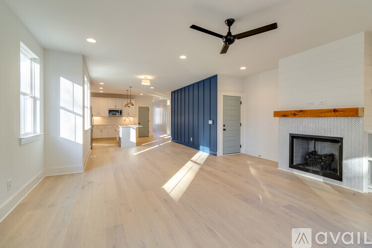 A spacious living room with a fireplace and a ceiling fan.