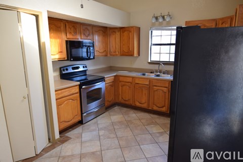 A kitchen with wooden cabinets and a black refrigerator.