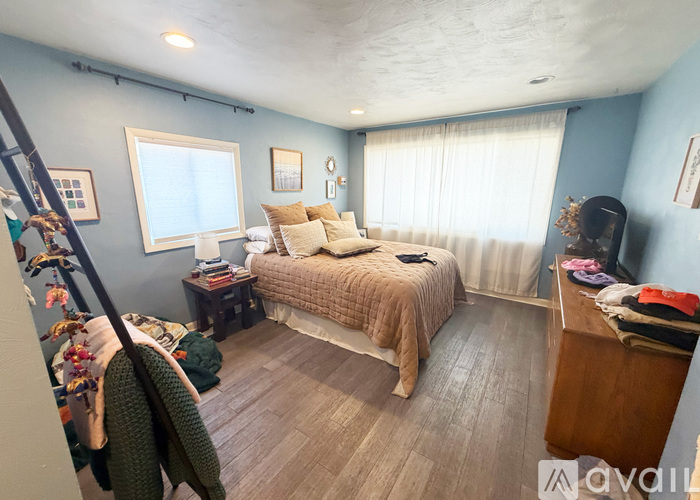A bedroom with a bed, a desk, and a window with curtains.