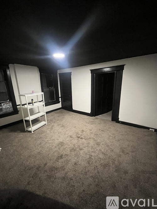 A room with a white shelving unit and a black door.