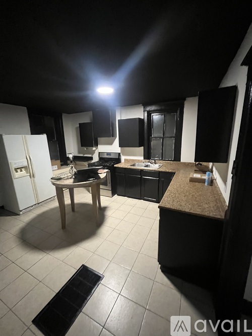 A kitchen with black cabinets and a table in the middle.