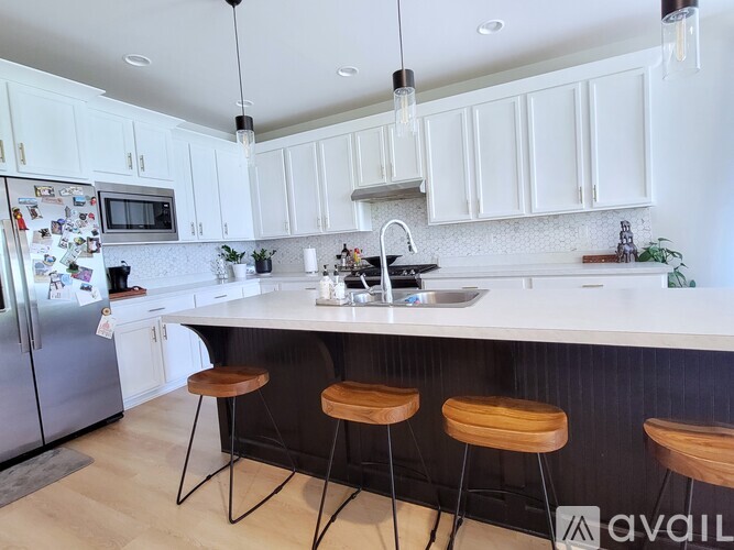 A kitchen with white cabinets and a black counter.