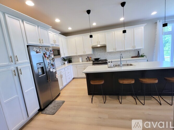 A kitchen with white cabinets and a black fridge.