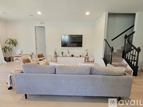 A living room with a grey couch and a staircase.