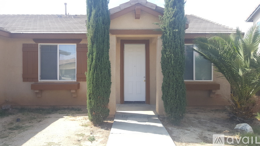 A house with a white door and two green trees in front.