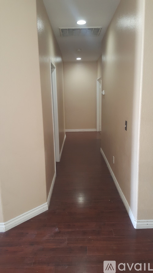 A long hallway with wood floors and white walls.