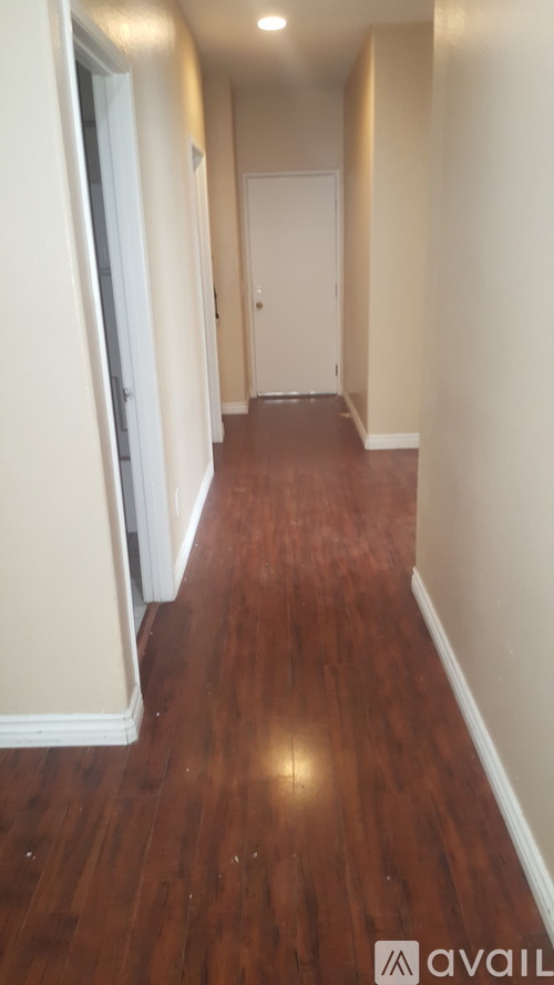 A long hallway with wood floors and white walls.