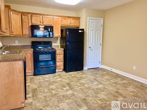 A kitchen with black appliances and wooden cabinets.