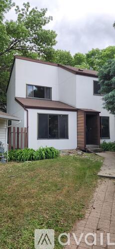 A modern two-story house with a white exterior and a brown roof.