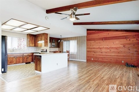 A spacious kitchen and living room with wooden floors and a ceiling fan.