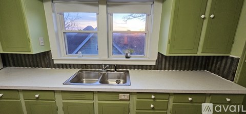 A kitchen with green cabinets and a window overlooking a snowy landscape.