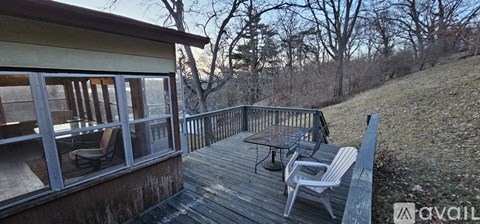 A wooden deck with a table and chairs overlooking a grassy area.