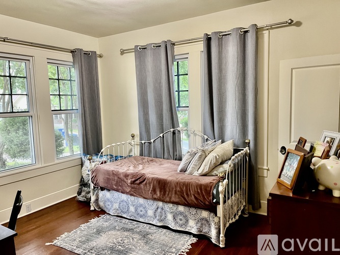 A bedroom with a bed, a chair, and a window with curtains.