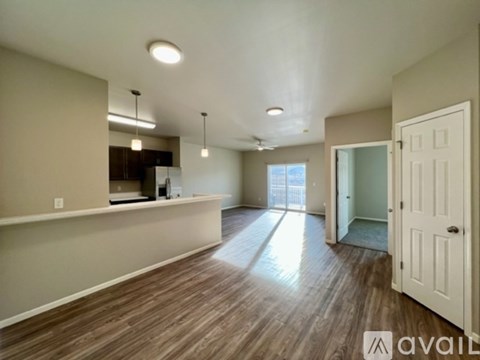 A spacious living room with hardwood floors and a kitchen area in the background.