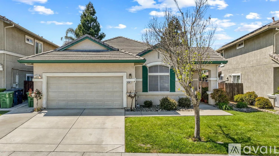 A house with a garage and a tree in front of it.
