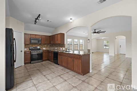 A spacious kitchen with a black refrigerator and wooden cabinets.