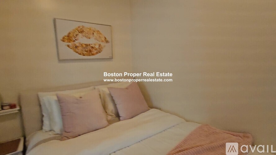 A bedroom with a bed, pillows, and a painting on the wall.
