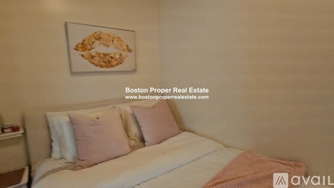 A bedroom with a bed, pillows, and a painting on the wall.