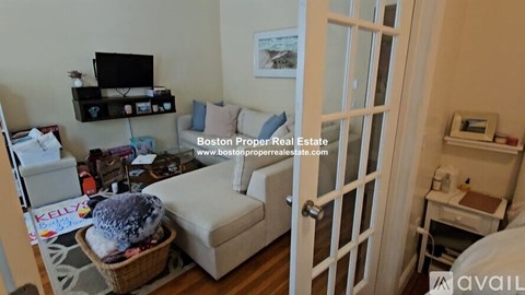 A living room with a couch, a TV, and a basket with a blue fluffy object on it.