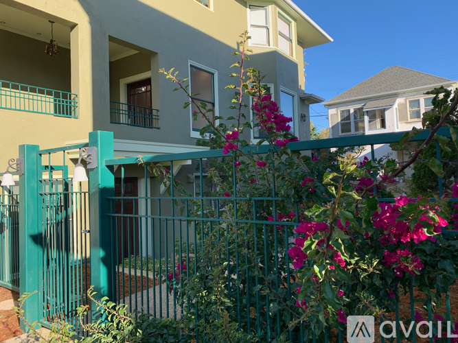 A house with a green gate and flowers in front.