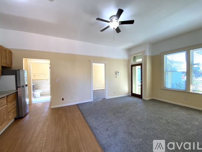 A spacious living room with a ceiling fan and hardwood floors.