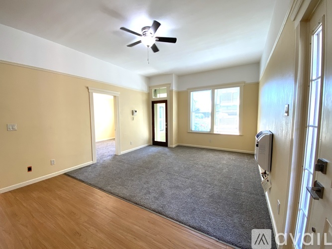 A spacious room with a ceiling fan and a rug on the floor.