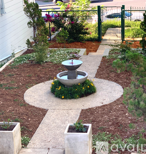 A garden with a fountain in the middle of a circular stone area.