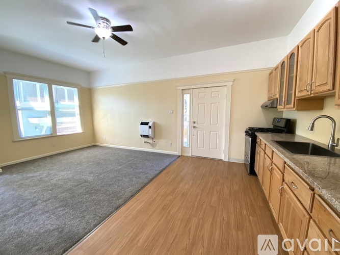 A room with wooden floors and a kitchen area with a sink and stove.