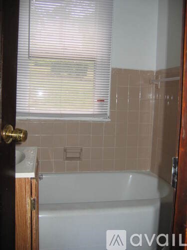 A bathroom with a tub and a window with blinds.