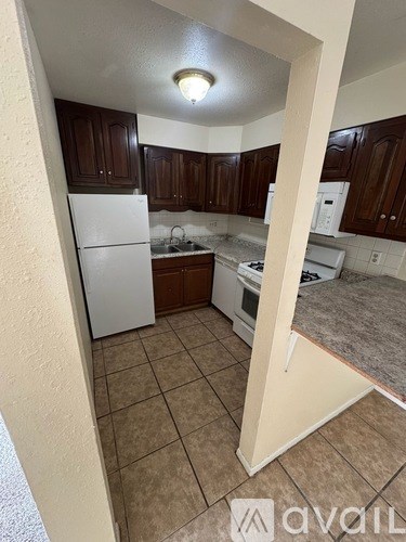 A kitchen with brown cabinets and a white refrigerator.