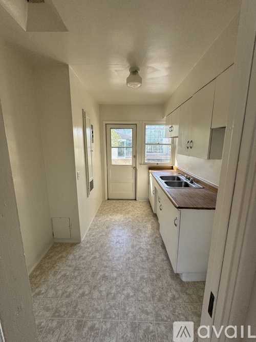 A kitchen with white cabinets and a tiled floor.