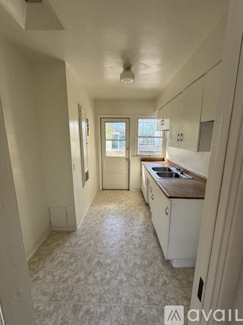 A kitchen with white cabinets and a tiled floor.