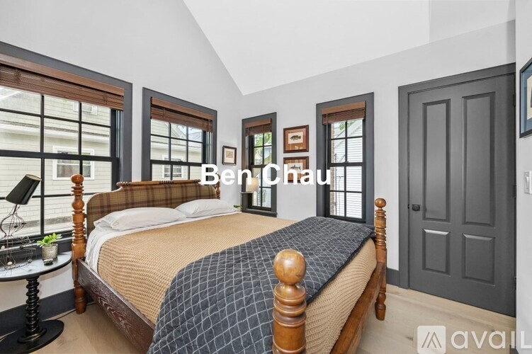 A bedroom with a large bed and a window with blinds.
