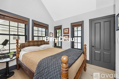 A bedroom with a large bed and a window with blinds.