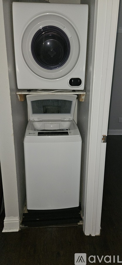A white washing machine with a black door is in a small space.