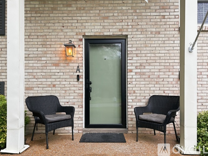 Two black chairs are placed on a gravel area in front of a brick building.