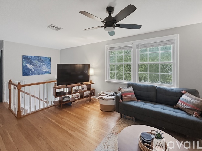 A living room with a couch, television, and a ceiling fan.