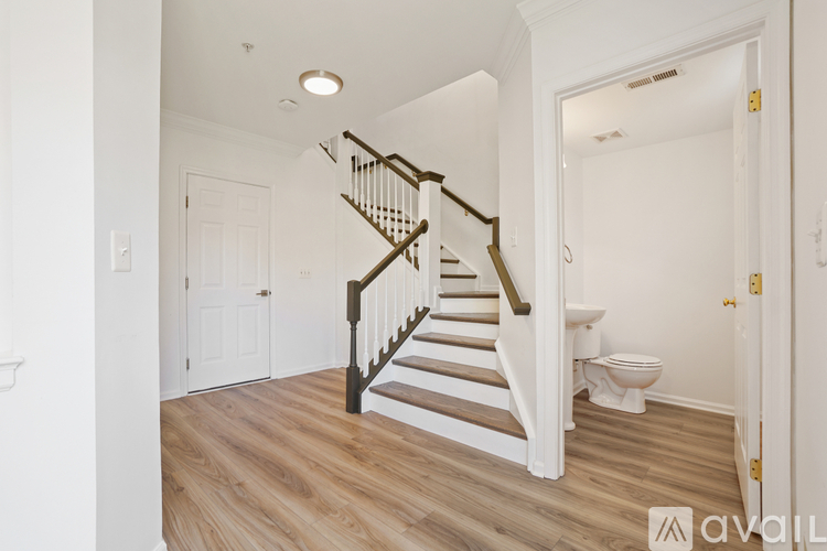 A wooden staircase with white railings leads to a second floor.