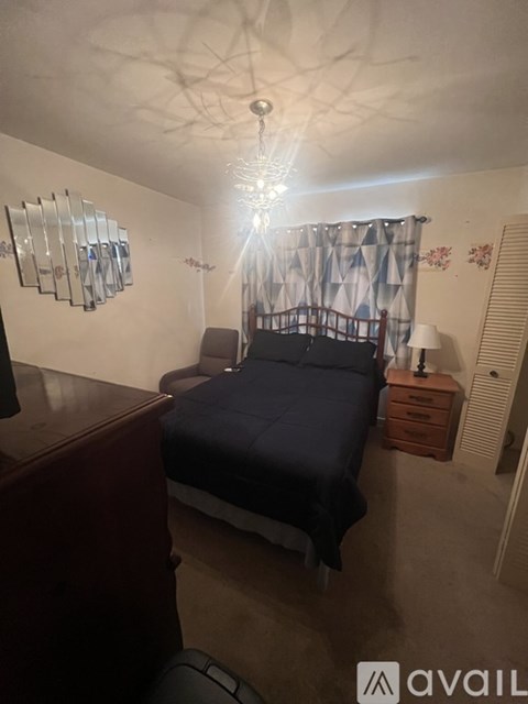 A bedroom with a bed, nightstand, and a mirror on the wall.