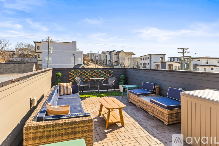 A patio with a table, chairs, and a couch with a backdrop of buildings.