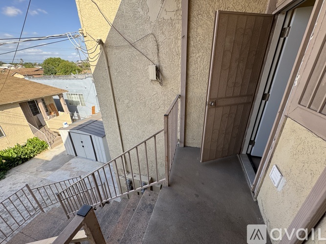 A staircase with a metal railing leads up to a door on a tan building.