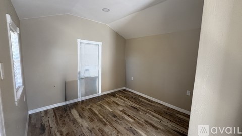 A room with wooden flooring and a window.