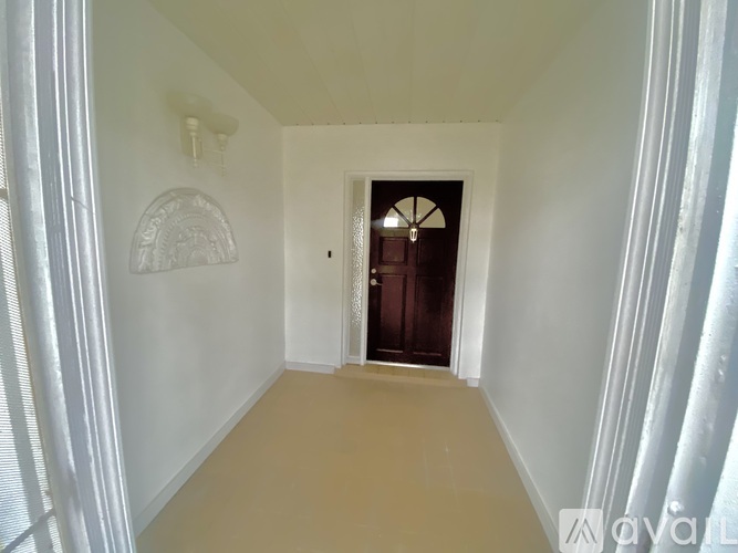 A hallway with a door at the end and a light fixture on the wall.