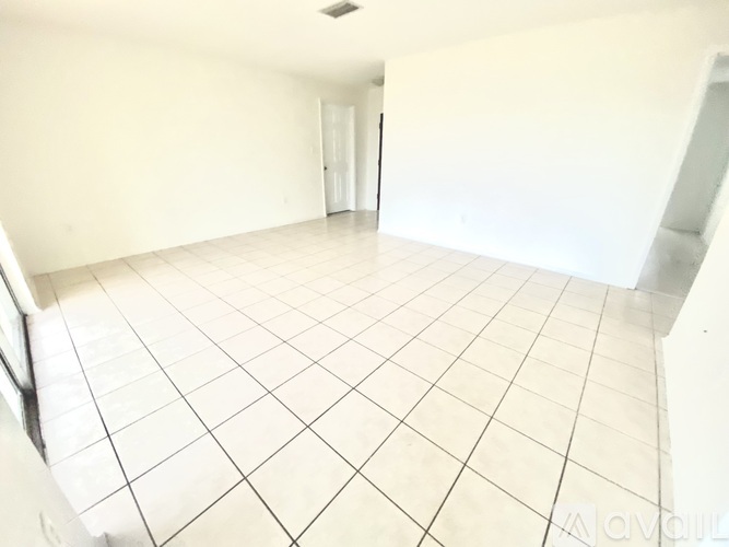 A room with white tiled flooring and a door in the background.
