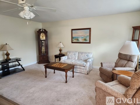 A living room with a couch, chair, and a table with a lamp on it.