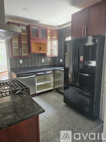 A kitchen with a black fridge and a black counter top.