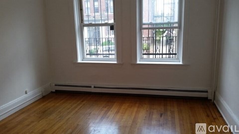 A room with wooden floors and two windows.